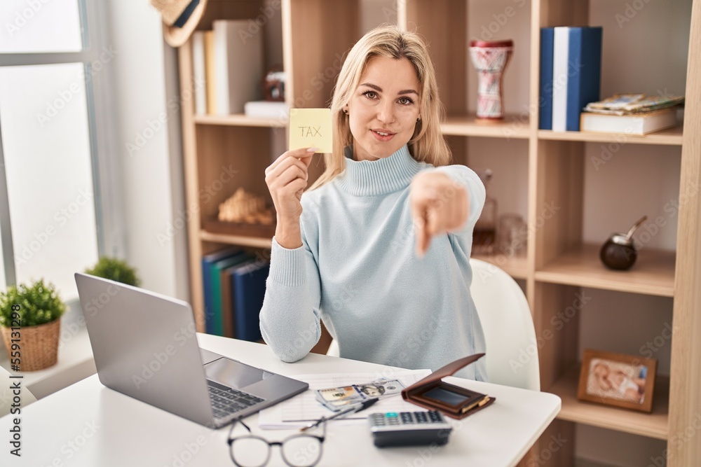 Young caucasian woman calculating money savings pointing with finger to the camera and to you, confident gesture looking serious Young caucasian woman calculating money savings pointing with finger to the camera and to you, confident gesture looking serious