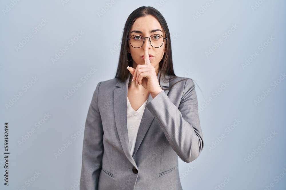 Hispanic business woman wearing glasses asking to be quiet with finger on lips. silence and secret concept. Hispanic business woman wearing glasses asking to be quiet with finger on lips. silence and secret concept.