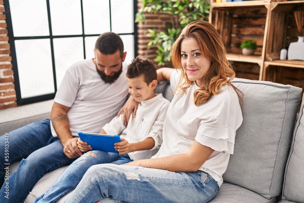 Family using touchpad hugging each other sitting on sofa at home Family using touchpad hugging each other sitting on sofa at home
