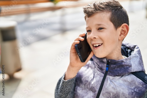 Blond child smiling confident talking on the smartphone at street