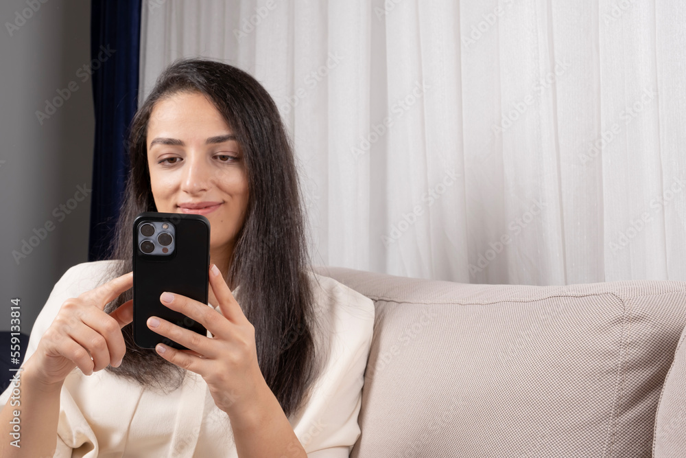 Using smartphone, Caucasian woman holding modern and using smartphone. Sitting home smiling chatting friend or surfing internet, social media application. Happy leisure. Copy space, technology concept Using smartphone, Caucasian woman holding modern and using smartphone. Sitting home smiling chatting friend or surfing internet, social media application. Happy leisure. Copy space, technology concept
