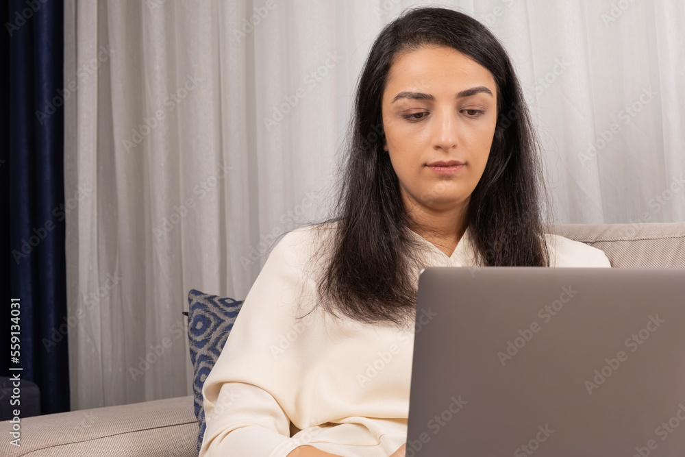 Using modern laptop, millennial caucasian woman sitting at home and using modern laptop. Freelance employee office worker at living room trying to get finish the project. Female coder or copywriter. Using modern laptop, millennial caucasian woman sitting at home and using modern laptop. Freelance employee office worker at living room trying to get finish the project. Female coder or copywriter.