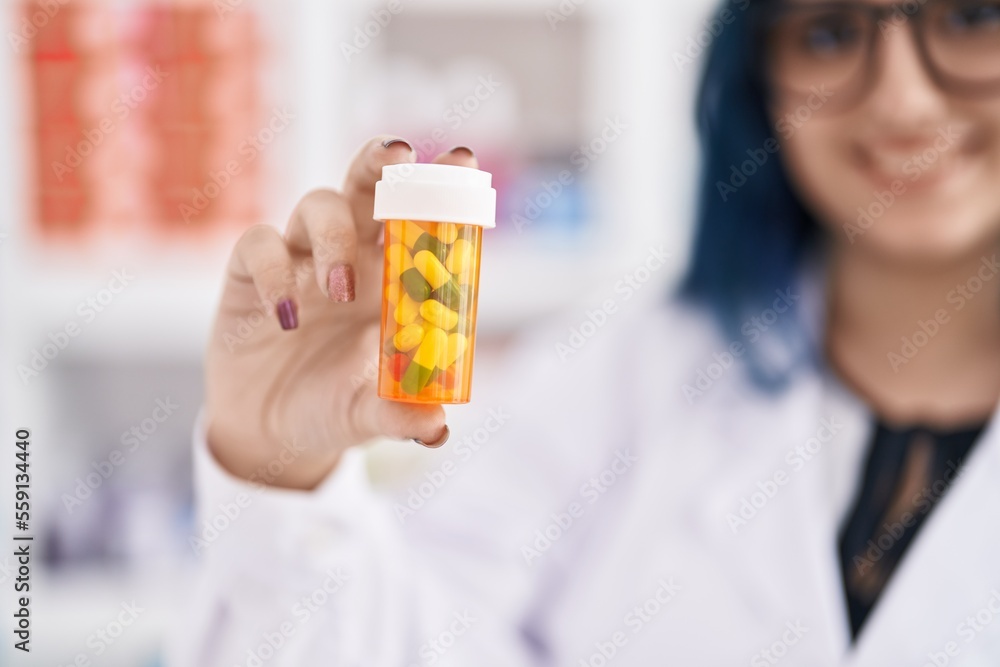 Young caucasian woman pharmacist smiling confident holding pills bottle at pharmacy Young caucasian woman pharmacist smiling confident holding pills bottle at pharmacy
