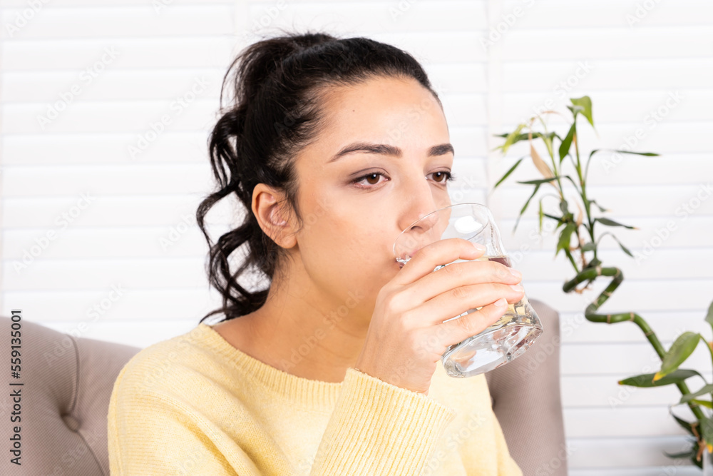 Drinking water, portrait of brunette woman drinking water. Caucasian girl enjoy pure fresh mineral water at home. Sitting armchair. Profile shot of thirsty lady holding glass of still aqua. Drinking water, portrait of brunette woman drinking water. Caucasian girl enjoy pure fresh mineral water at home. Sitting armchair. Profile shot of thirsty lady holding glass of still aqua.