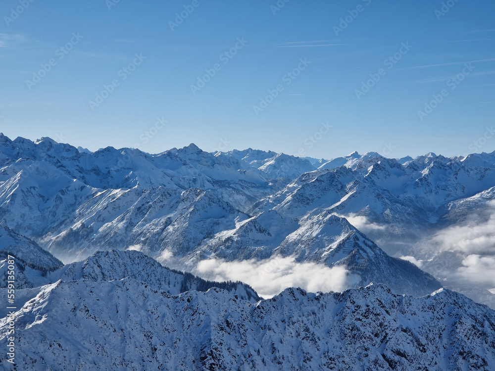 Bergpanorama mit Schnee auf den Gipfeln und Wolken im Tal