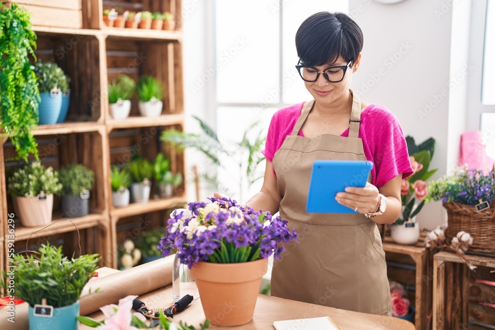Middle age chinese woman florist smiling confident using touchpad at flower shop Middle age chinese woman florist smiling confident using touchpad at flower shop