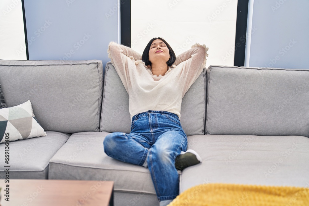 Young chinese woman relaxed with hands on head sitting on sofa at home Young chinese woman relaxed with hands on head sitting on sofa at home