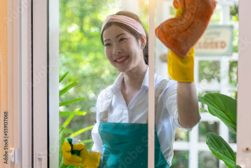Happy Young Asian woman cleaning window at home, Housewife Cleaning or Housework Concept.