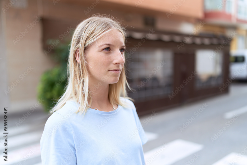 Young blonde woman looking to the side with serious expression at coffee shop terrace Young blonde woman looking to the side with serious expression at coffee shop terrace