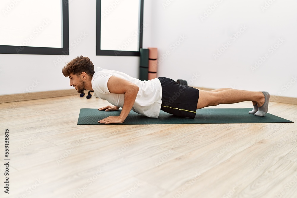 Young arab man smiling confident training abs exercise at sport center