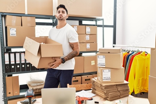 Young hispanic man working at small business ecommerce looking at the camera blowing a kiss being lovely and sexy. love expression.