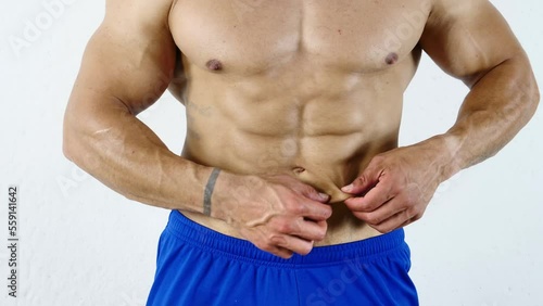 Fit, athletic muscular man pinching his stomach skin