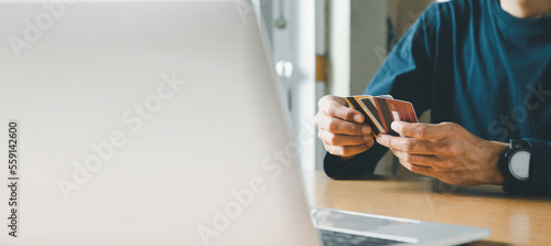 Man hand holding credit card and using laptop at home, Businessman or entrepreneur working, Online shopping, e-commerce, internet banking, spending money concept.