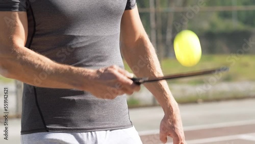Pickleball paddle and yellow ball close up, man playing pickleball game, hitting pickleball yellow ball with paddle, outdoor sport leisure activity.