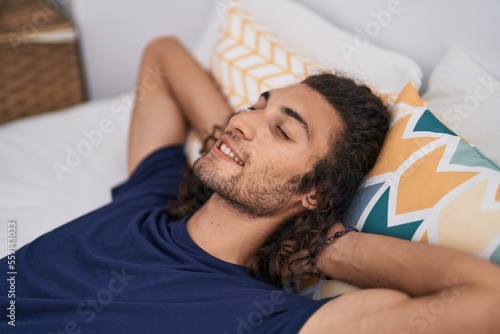 Young hispanic man smiling confident lying on bed at bedroom