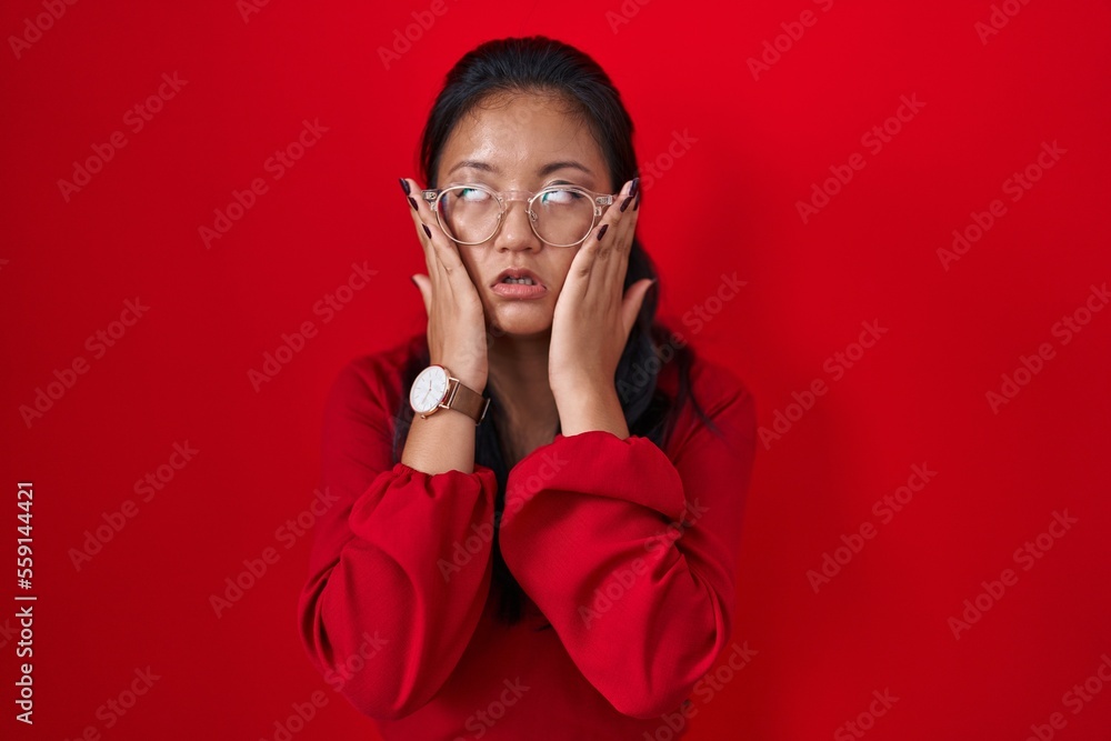Asian young woman standing over red background tired hands covering face, depression and sadness, upset and irritated for problem Asian young woman standing over red background tired hands covering face, depression and sadness, upset and irritated for problem
