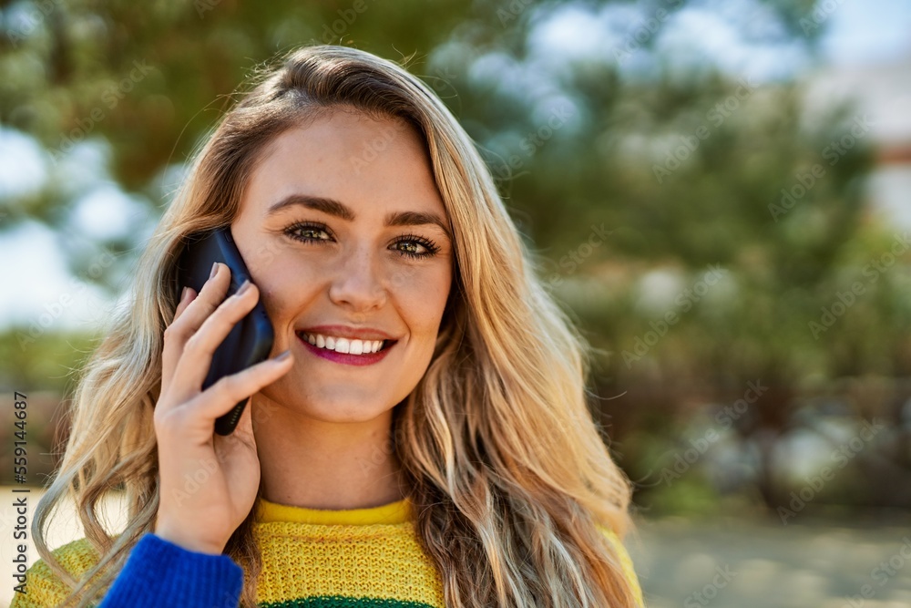 Young blonde woman speaking on the phone at the park Young blonde woman speaking on the phone at the park