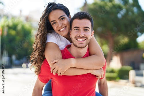 Young hispanic couple smiling confident hugging each other holding on back at street