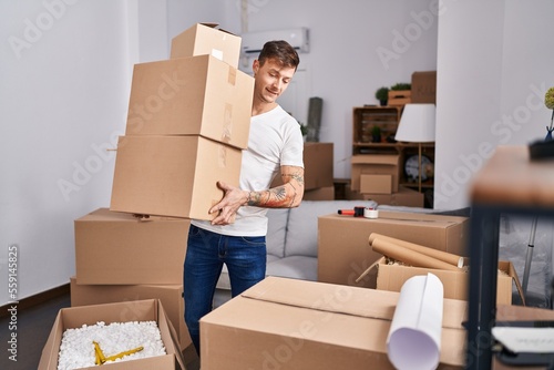 Young man smiling confident holding packages at new home
