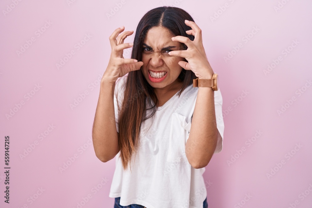 Young arab woman standing over pink background shouting frustrated with rage, hands trying to strangle, yelling mad Young arab woman standing over pink background shouting frustrated with rage, hands trying to strangle, yelling mad