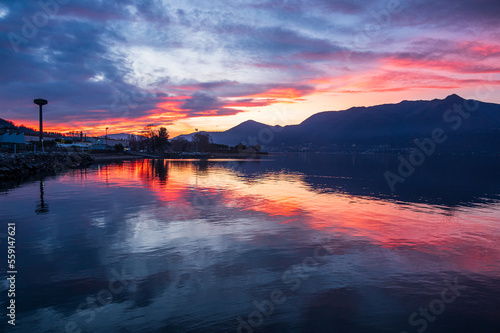Beautiful colorful sunset with clouds and mountains reflecting on Lake Maggiore in Luino