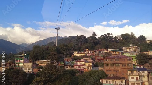 Shoot from inside the cabin of a ropeway from Dharamshala to Mcleod Ganj. Skyway, India. Cable car. Panoramic of the hills and traditional houses. Cabin passing. photo