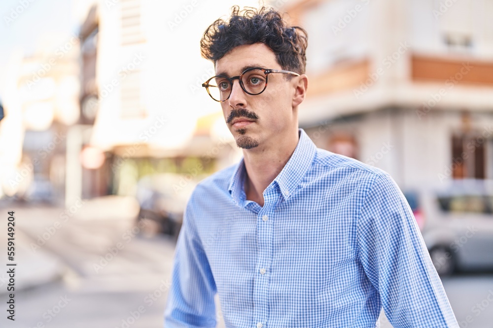 Young caucasian man looking to the side with serious expression at street Young caucasian man looking to the side with serious expression at street