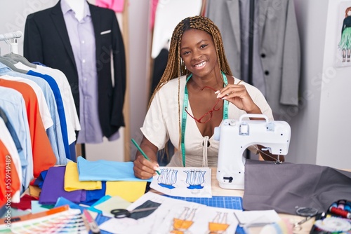 African american woman tailor smiling confident drawing clothing design at tailor shop