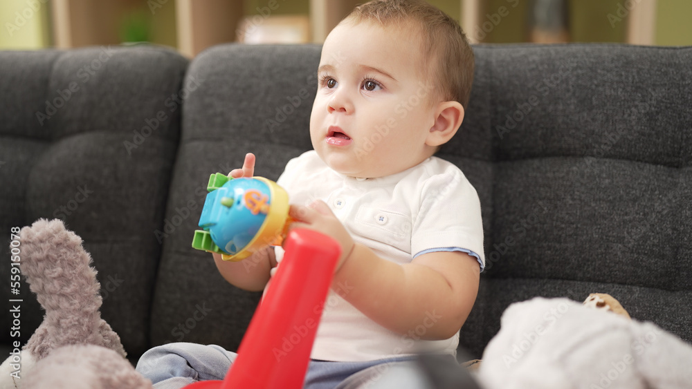 Adorable toddler playing with toys sitting on sofa at home Adorable toddler playing with toys sitting on sofa at home
