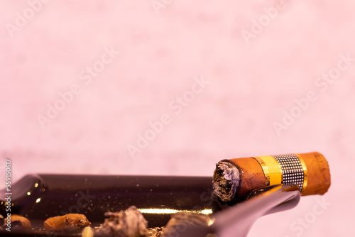 Close up of a lit cigar in a black ashtray