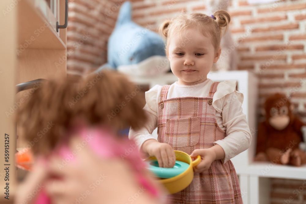 Adorable caucasian girl playing with play kitchen standing at kindergarten Adorable caucasian girl playing with play kitchen standing at kindergarten