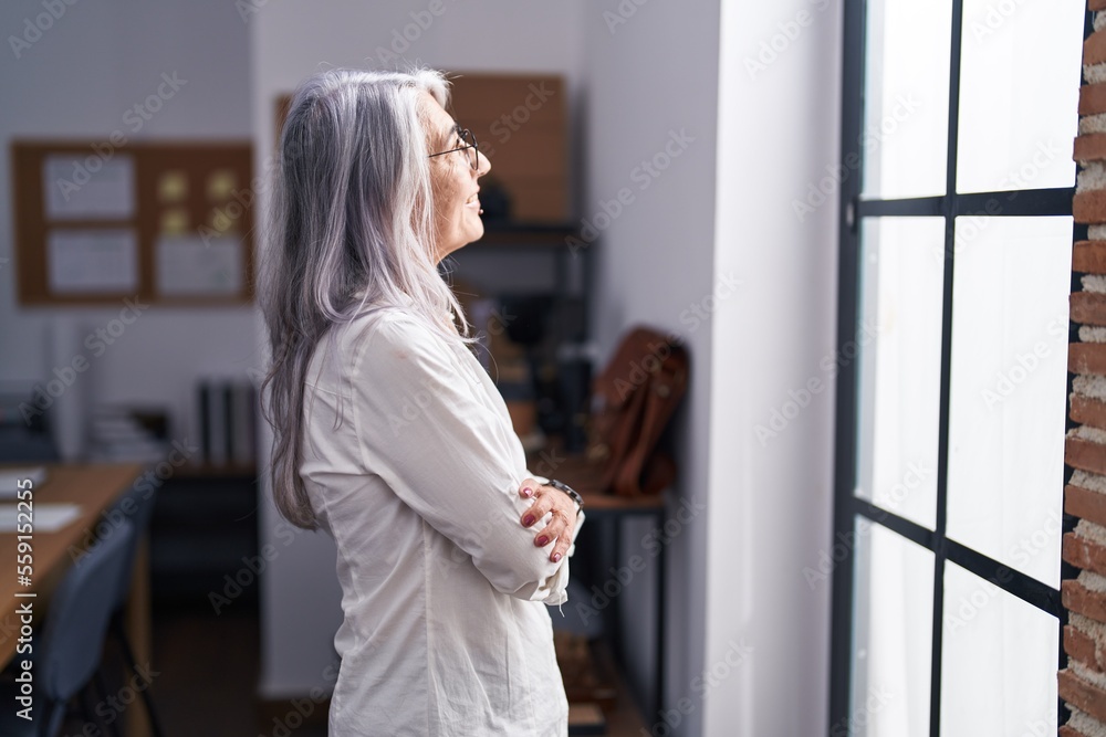 Middle age grey-haired woman business worker looking throw the window at office