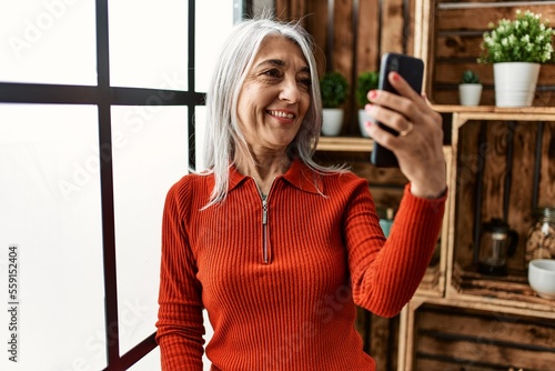 Middle age grey-haired woman smiling confident having video call at home