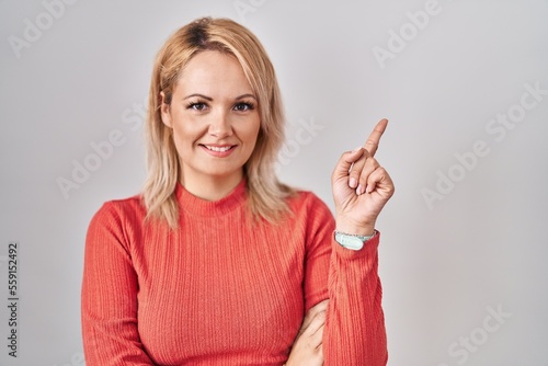 Wallpaper Mural Blonde woman standing over isolated background with a big smile on face, pointing with hand finger to the side looking at the camera. Torontodigital.ca