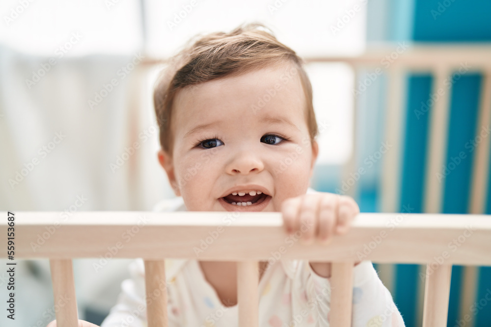 Adorable caucasian baby smiling confident standing on cradle at bedroom