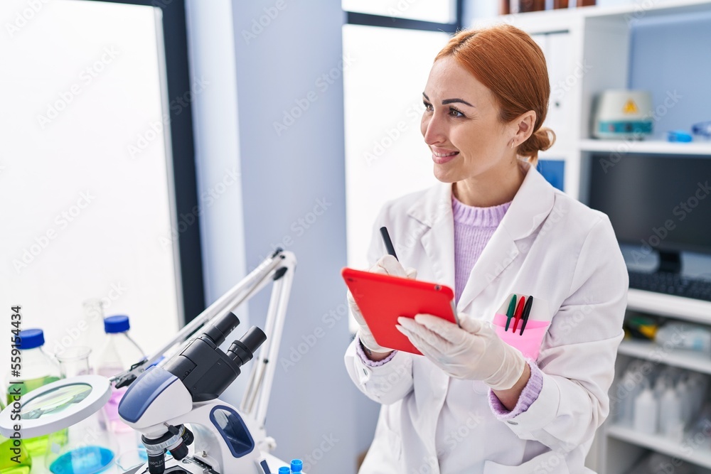 Young caucasian woman scientist smiling confident using touchpad at laboratory Young caucasian woman scientist smiling confident using touchpad at laboratory