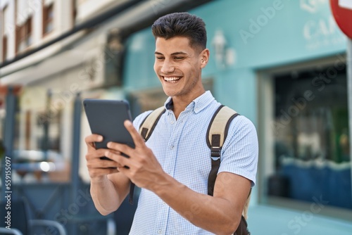 Young hispanic man student using touchpad at street