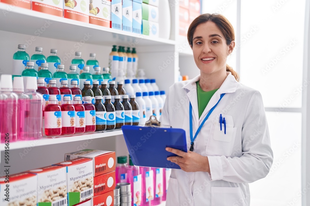 Young woman pharmacist smiling confident writing on document at pharmacy Young woman pharmacist smiling confident writing on document at pharmacy
