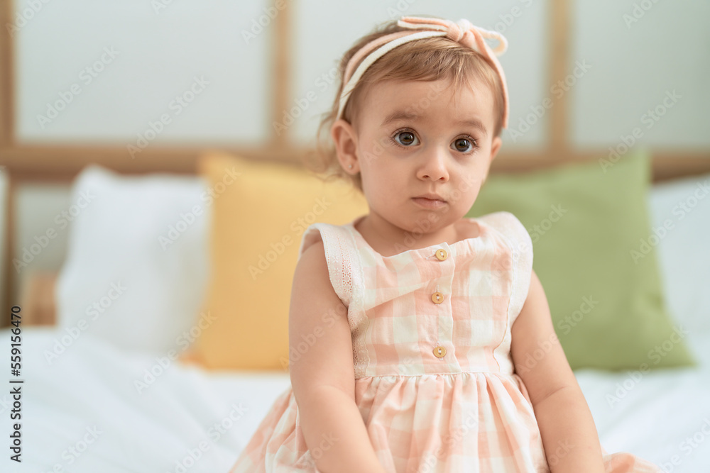 Fototapeta premium Adorable caucasian girl sitting on bed with relaxed expression at bedroom