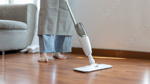 Young housewife mopping and cleaning the wooden floor, Use an antiseptic mop to clean the living room, Doing homework cleaning routine, Housewife's duty, Professional sanitation service concept.