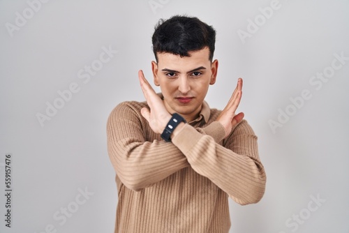 Non binary person standing over isolated background rejection expression crossing arms doing negative sign, angry face