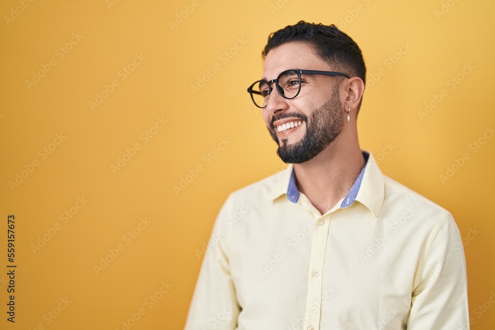 Hispanic young man wearing business clothes and glasses looking away to side with smile on face, natural expression. laughing confident. Hispanic young man wearing business clothes and glasses looking away to side with smile on face, natural expression. laughing confident.