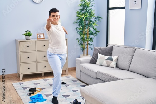 Young non binary man doing yoga exercise sitting on floor at home