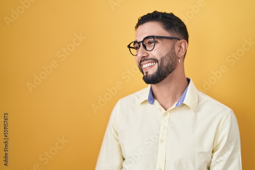 Hispanic young man wearing business clothes and glasses looking away to side with smile on face, natural expression. laughing confident. © Krakenimages.com