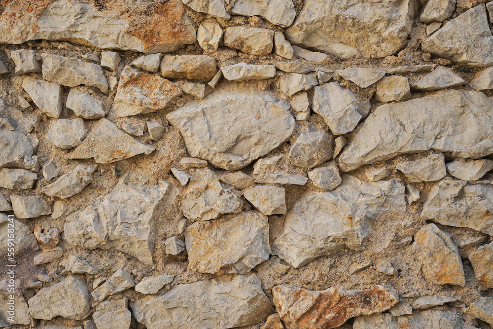 Rough stone wall, laying the foundation of an old house or foundation of a structure, idea for a background or wallpaper Rough stone wall, laying the foundation of an old house or foundation of a structure, idea for a background or wallpaper
