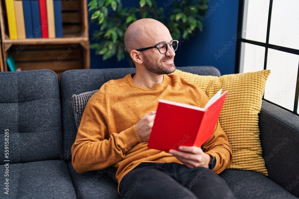 Young man reading book sitting on sofa at home Young man reading book sitting on sofa at home
