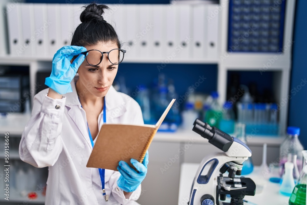 Young caucasian woman scientist reading book at laboratory Young caucasian woman scientist reading book at laboratory