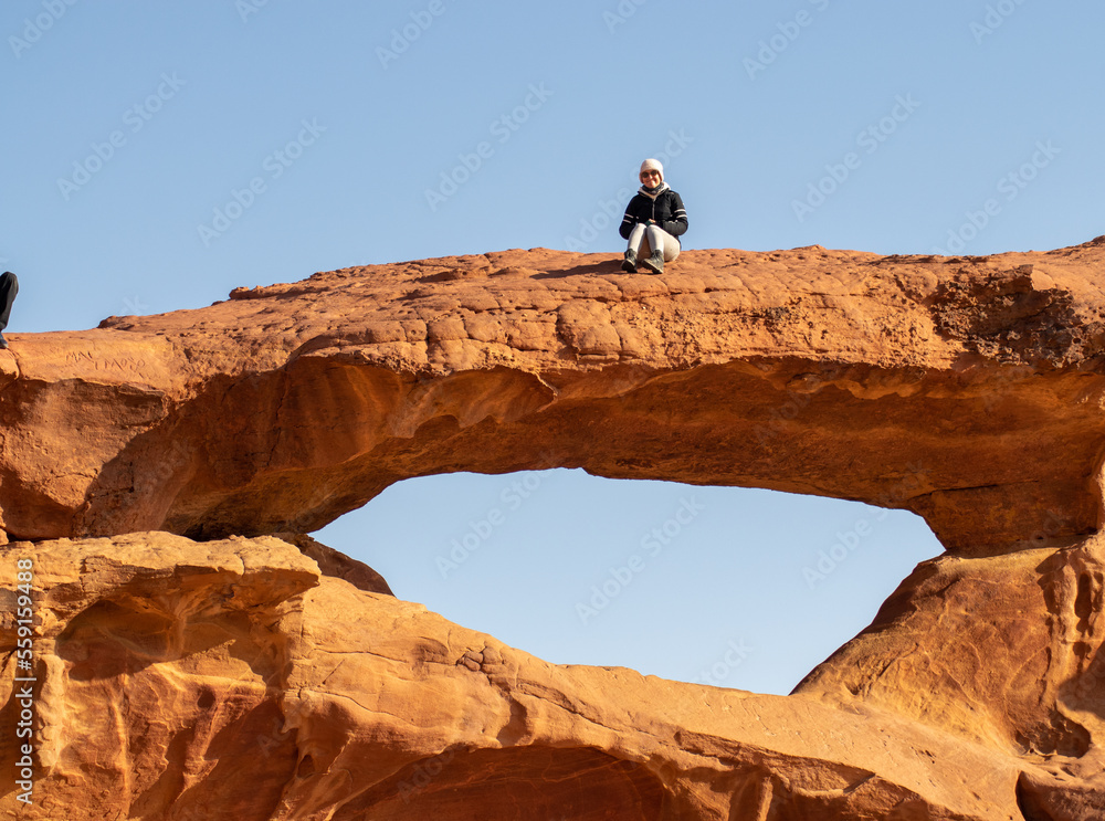 person on an arch on a sunny day in wadi rum, jordan