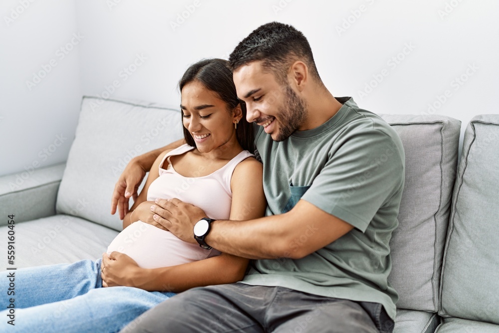 Latin man and woman couple hugging each other expecting baby at home Latin man and woman couple hugging each other expecting baby at home
