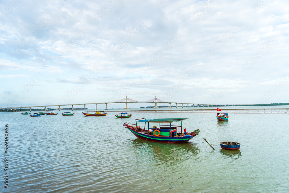 The scenery of the estuary with the bridge crossing is very beautiful, the sky is clear and the small boats are ready to go fishing
